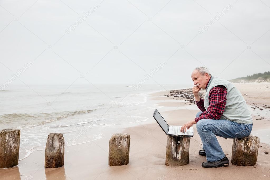 Old man with notebook on beach