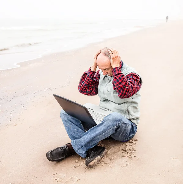 Gubbe med anteckningsboken på stranden — Stockfoto