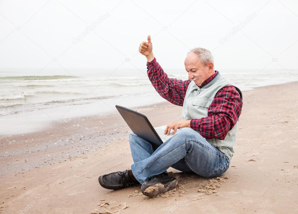 Old man with notebook on beach