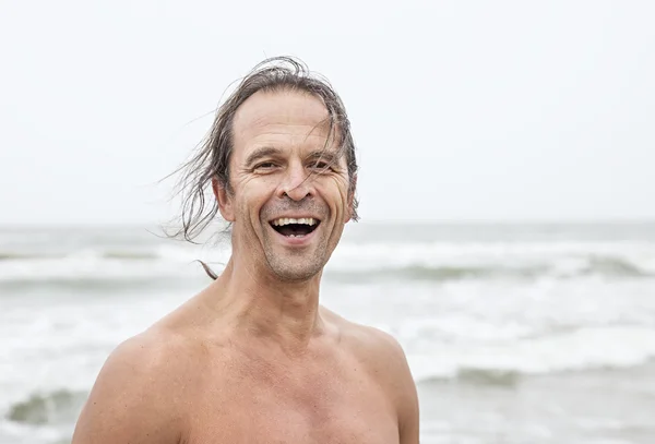 Homme debout à la plage souriant — Photo