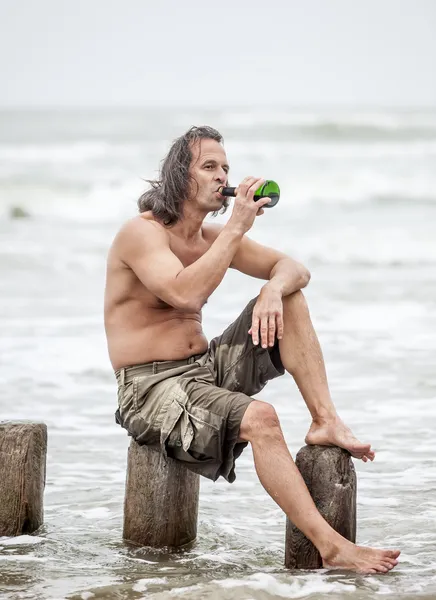 Hombre sentado cerca del mar y bebiendo alcohol — Foto de Stock