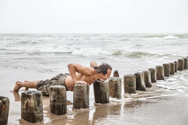 Homme faisant des pompes sur la plage — Photo