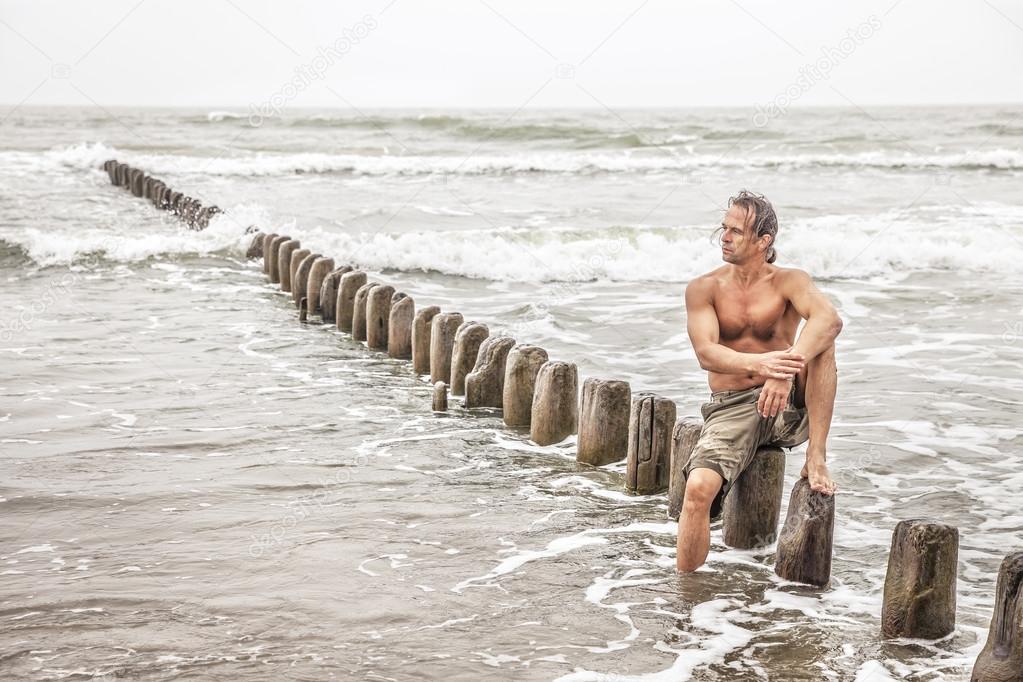 Middle-aged man sitting near the sea