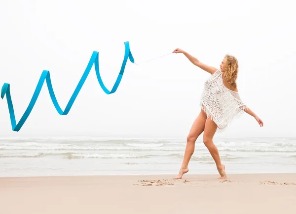 Гимнастка танцует с лентой на пляже — стоковое фото
