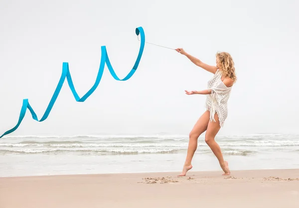 Turnerin tanzt mit Schleife am Strand — Stockfoto