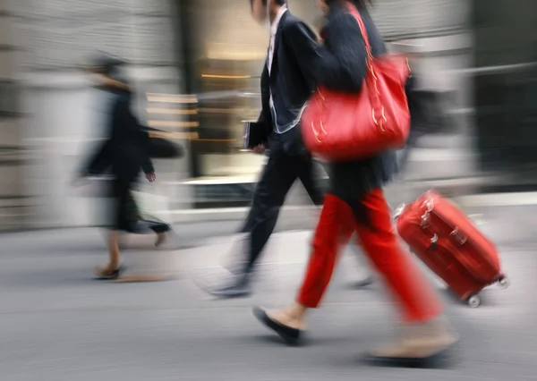 Persone con una borsa rossa e una valigia che camminano per strada — Foto Stock