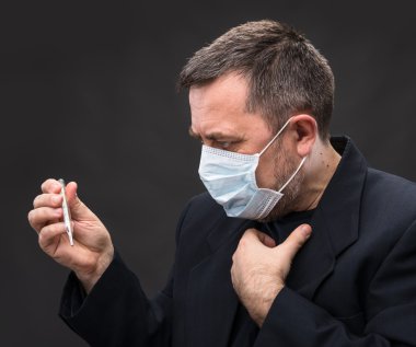 Man in medical mask with a thermometer clipart