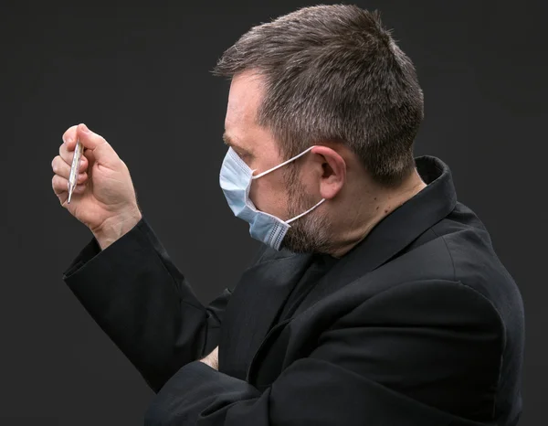 Man in medical mask with a thermometer — Stock Photo, Image