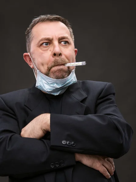 Homem em máscara médica com um termômetro — Fotografia de Stock