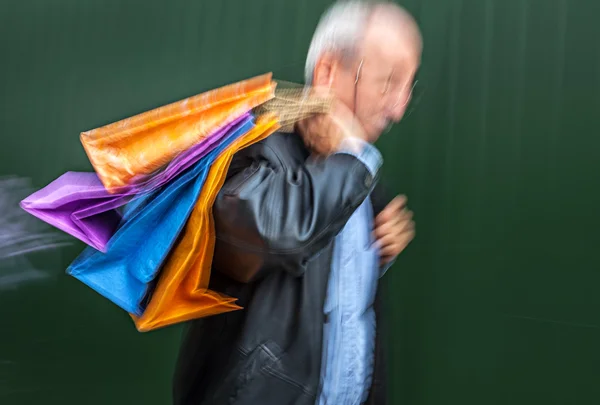 Holiday sales. An elderly man with many shopping bags in his han — Stock Photo, Image
