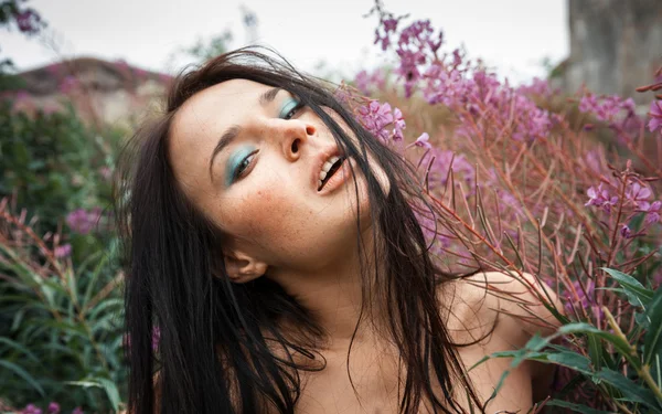 Mooi sproeterig meisje onder de bloemen — Stockfoto