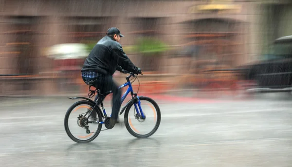 Radfahrer fährt an einem regnerischen Tag durch die Straßen — Stockfoto