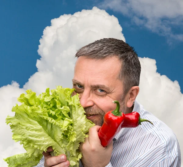 Hombre sosteniendo lechuga contra el cielo azul — Foto de Stock