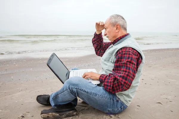 Gubbe med anteckningsboken på stranden — Stockfoto