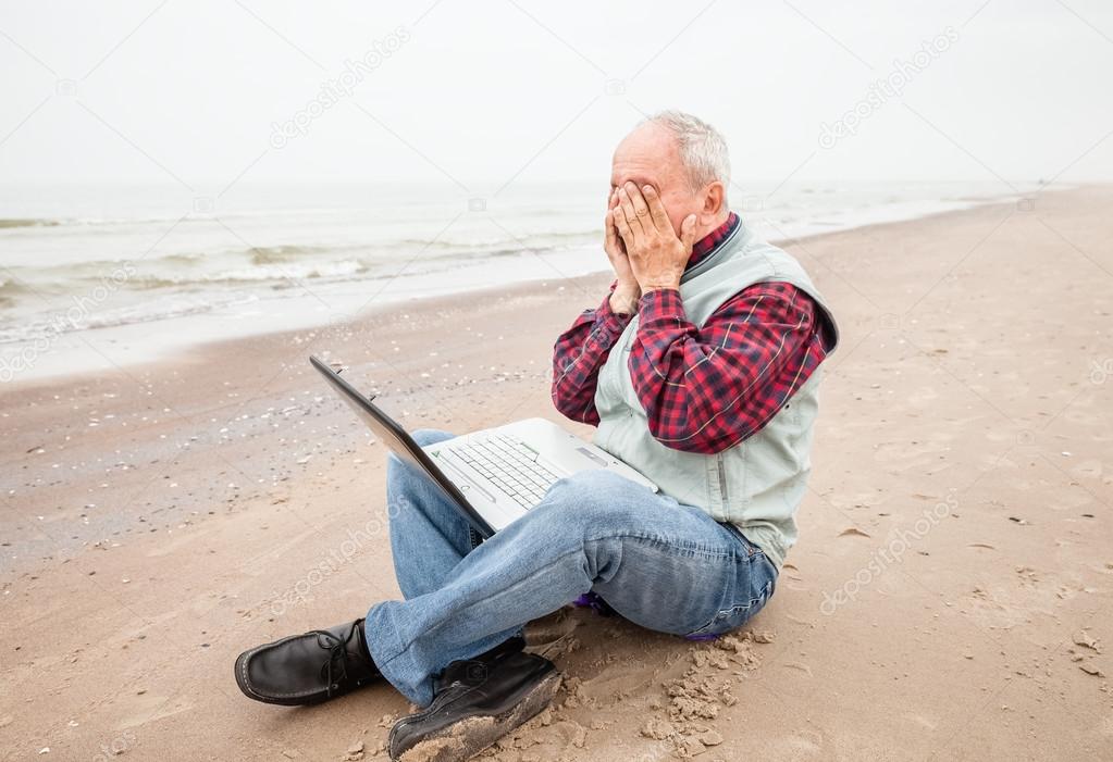 Old man with notebook on beach