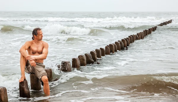 Мужчина средних лет, сидящий у моря — стоковое фото