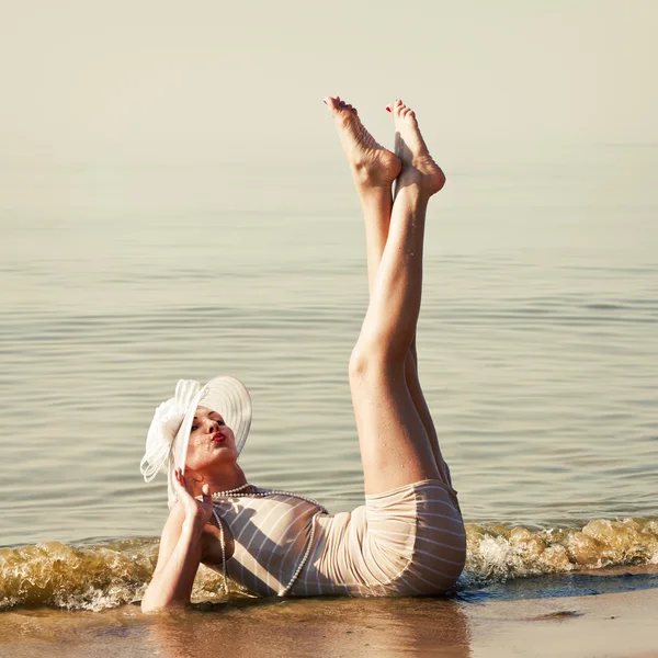 Kvinnan i vit hatt poserar mot havet — Stockfoto