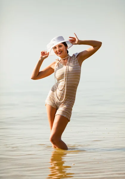 Frau mit weißem Hut posiert gegen das Meer — Stockfoto