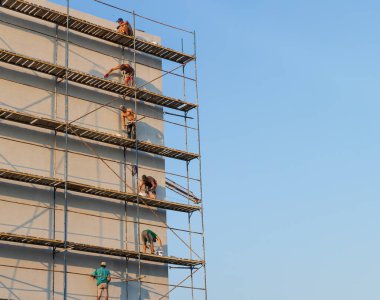 UZHGOROD, UKRAINE - 16 Eylül 2021: İnşaat işçileri evin dış yüzeyine dekoratif alçı koyuyorlar. Termal yalıtım ve boyama çalışmalarını ön plana çıkar