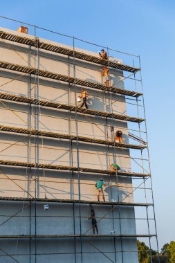 UZHGOROD, UKRAINE - 16 Eylül 2021: İnşaat işçileri evin dış yüzeyine dekoratif alçı koyuyorlar. Termal yalıtım ve boyama çalışmalarını ön plana çıkar