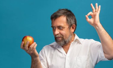 Sağlıklı yaşam tarzı ve elma diyeti. Beyaz tişörtlü, kırmızı elmalı orta yaşlı bir adam..