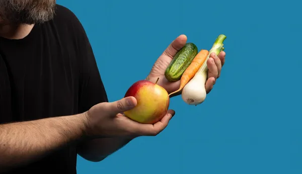 健康的なライフスタイルと菜食主義 黒のTシャツを着た中年の男が果物や野菜を手に — ストック写真