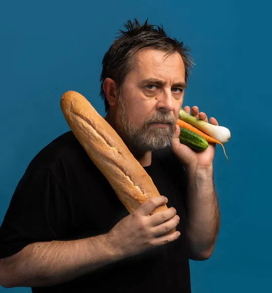 健康的なライフスタイルのコンセプト 難しい選択だ より良いパンや野菜は何ですか 黒のTシャツを着た中年の男がリンゴを片手に持ち もう片方の手にパンを持っている — ストック写真