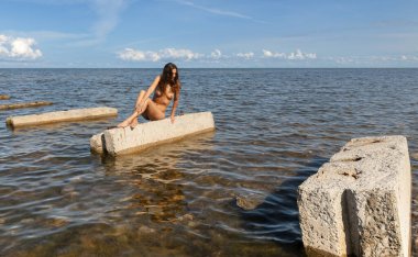 Bu yalanı denizde bir güneşli yaz gün Beton üzerinde güneşlenme üzerinde genç çıplak kadın tabaka