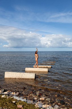 Bu yalanı denizde bir güneşli yaz gün Beton üzerinde güneşlenme üzerinde genç çıplak kadın tabaka