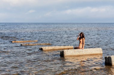 Bu yalanı denizde bir güneşli yaz gün Beton üzerinde güneşlenme üzerinde genç çıplak kadın tabaka