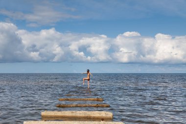 Bu yalanı denizde bir güneşli yaz gün Beton üzerinde güneşlenme üzerinde genç çıplak kadın tabaka