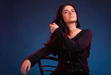 Mavi arka plan ve kırmızı arka plan karşısında esmer bir kadının stüdyo portresi.