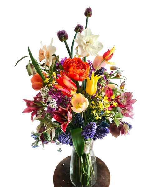 The art of flower arrangement. Bouquet of colorful garden flowers isolated on white background. The composition includes tulips, daffodils, alliums, muscari, lunaria, fritillaria and hellebore