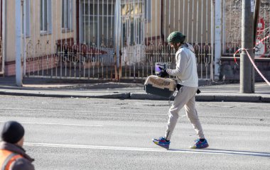 KYIV, UKRAINE - 25 Şubat 2022 Ukrayna Savaşı. Silahlı bir mahalle sakini taşıyıcı bir kedi ve akvaryumda bir balık taşıyor. Son bombardımandan zarar gören bir apartmandan kurtardığı bir balık.