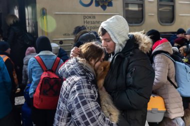 KYIV, UKRAINE - Mar. 11, 2022: Ukrayna savaşı. Kyiv tren istasyonundaki insanlar ülkenin batı güvenli bölgelerine tahliye edildi. Trene binmeden önce köpek kucaklaşması yapan genç bir çift.