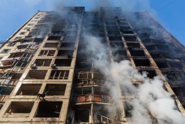 KYIV, UKRAINE - Mar. 15, 2022: War in Ukraine. General view of a badly damaged residential building in the smoke from the fire that was hit by a Russian shell. clipart