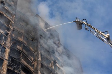 KYIV, UKRAINE - Mar. 15, 2022: Ukrayna 'da savaş. Rus bombasının vurduğu bir binada itfaiyeciler yangınla mücadele ediyor..