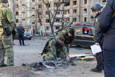 KYIV, UKRAINE - Mar. 20, 2022: Rus roketinin Kyiv 'e yaptığı saldırıdan sonra bina enkazın düşmesiyle hasar gördü. Polis, konut binasına zarar veren bir merminin parçalarını inceliyor.