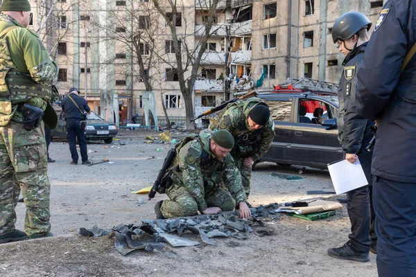 KYIV, UKRAINE - Mar. 20, 2022: Rus roketinin Kyiv 'e yaptığı saldırıdan sonra bina enkazın düşmesiyle hasar gördü. Polis, konut binasına zarar veren bir merminin parçalarını inceliyor.