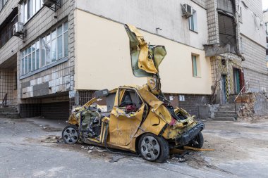 KYIV, UKRAINE - Mar. 31, 2022: Ukrayna savaşı. Rus roketinin Kyiv 'e yaptığı saldırıdan sonra yıkılan enkazın yol açtığı hasarlı binanın yakınındaki kırık ve parçalanmış yolcu vagonu.