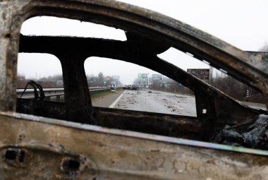 KYIV REG, UKRAINE - Nisan. 02, 2022: Kyiv-Zhytomyr karayolunda tahrip edilmiş ve yanmış bir araba görüldü..