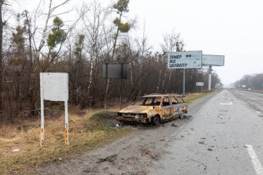 KYIV REG, UKRAINE - Nisan. 02, 2022: Kyiv-Zhytomyr karayolunda tahrip edilmiş ve yanmış bir araba görüldü..