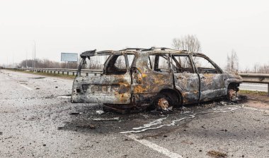 KYIV REG, UKRAINE - Nisan. 02, 2022: Kyiv-Zhytomyr karayolunda tahrip edilmiş ve yanmış bir araba görüldü..