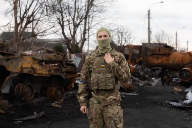 BuCHA, UKRAINE - Nisan. 06, 2022: Ukrayna ordusu imha edilmiş Rus askeri teçhizatının arka planına karşı poz verdi. Bucha sokaklarındaki Rus işgalcilerinin askeri teçhizatı yok edildi.