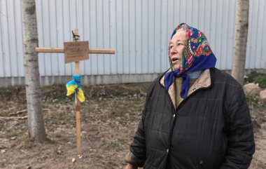 BuCHA, UKRAINE - Nisan. 06, 2022: Yakınlarının mezarının yakınında yaşayan bir kadın. 