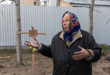 BuCHA, UKRAINE - Nisan. 06, 2022: Yakınlarının mezarının yakınında yaşayan bir kadın. 
