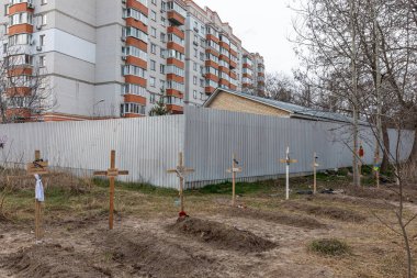 BuCHA, UKRAINE - Nisan. 06, 2022: Ukrayna 'nın Ukrayna' nın Kyiv kenti yakınlarındaki Bucha kentinde ele geçirilen apartman bloklarının yanındaki cesetlerle birlikte mezarlar.