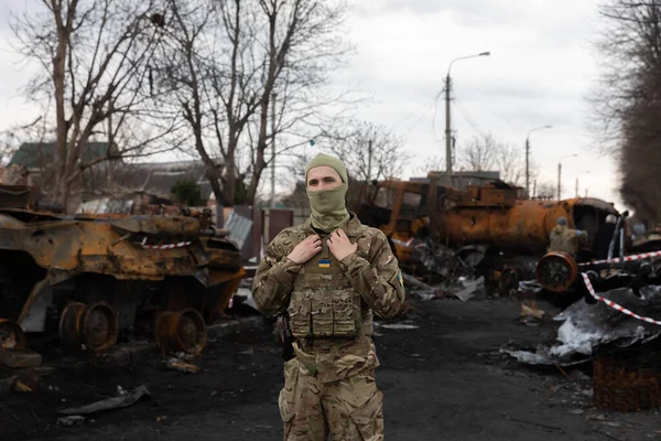 BuCHA, UKRAINE - Nisan. 06, 2022: Ukrayna ordusu imha edilmiş Rus askeri teçhizatının arka planına karşı poz verdi. Bucha sokaklarındaki Rus işgalcilerinin askeri teçhizatı yok edildi.