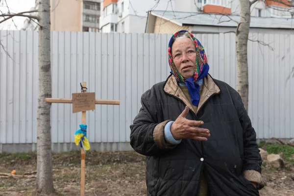 BuCHA, UKRAINE - Nisan. 06, 2022: Yakınlarının mezarının yakınında yaşayan bir kadın. 