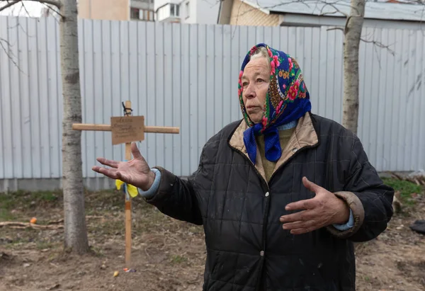 BuCHA, UKRAINE - Nisan. 06, 2022: Yakınlarının mezarının yakınında yaşayan bir kadın. 